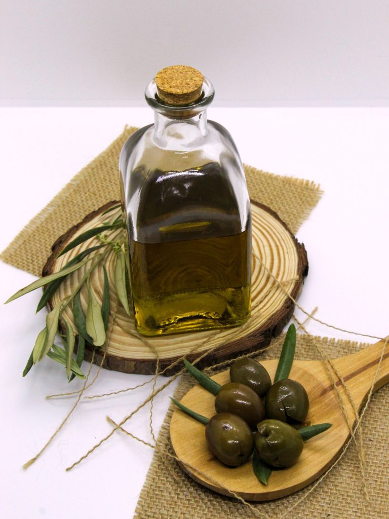 Botella de aceite de oliva virgen extra junto a una rama de olivo